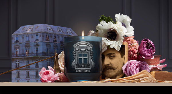Bougie parfumée Marcel Proust au milieu d'un décor de fleurs et de photos